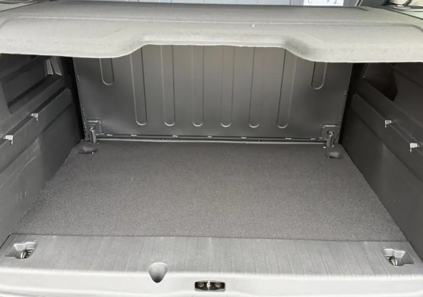 Coffre spacieux du Peugeot Rifter gris acier, vue arrière ouverte avec cache-bagages déployé.