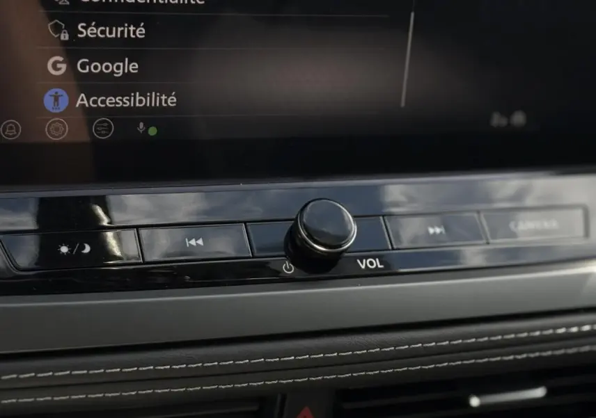 Gros plan sur la console centrale du Nissan Qashqai 2025, bouton volume et commandes tactiles sous écran tactile.