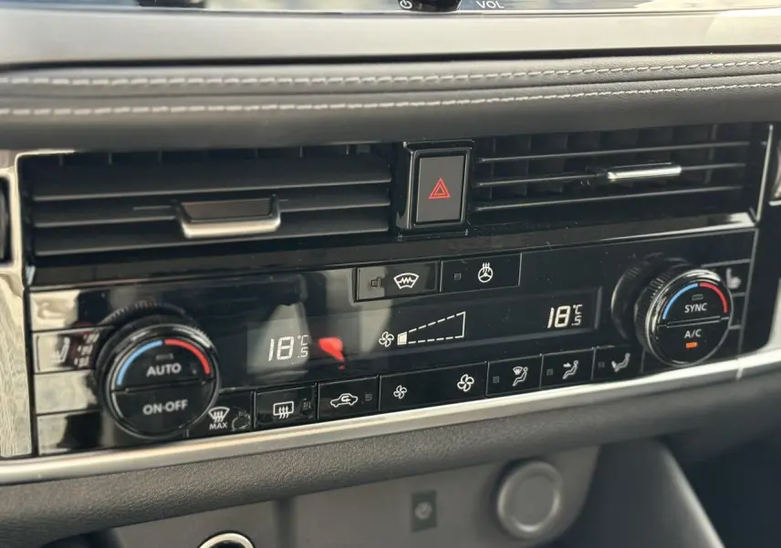 Détail de la console centrale noire du Nissan Qashqai 2025 avec commandes de climatisation bi-zone et bouton de démarrage.