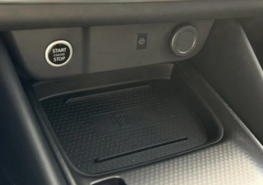 Gros plan sur le chargeur à induction noir dans l'habitacle du Nissan Qashqai gris Ceramic, avec bouton Start/Stop visible.