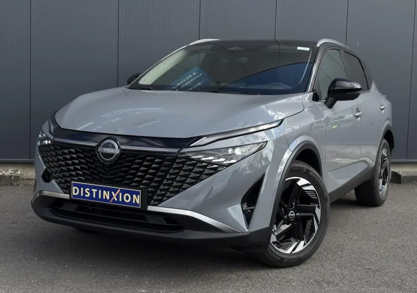 Nissan Qashqai gris Ceramic en 3/4 avant droit, avec calandre noire distinctive et jantes alliage 18 pouces bicolores.