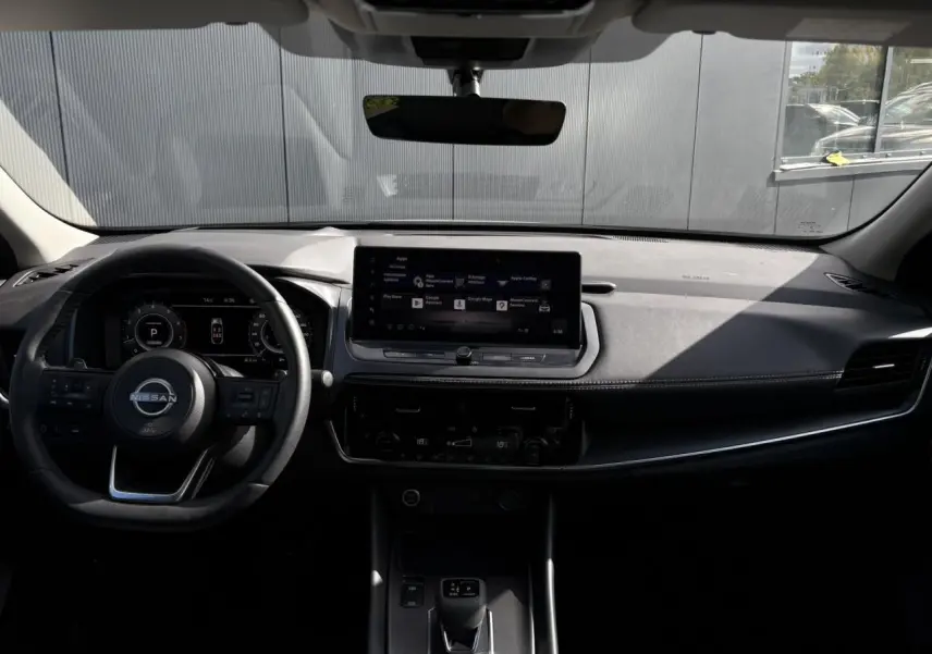 Intérieur du Nissan Qashqai 2025 avec tableau de bord noir, écran tactile central et volant cuir multifonction.