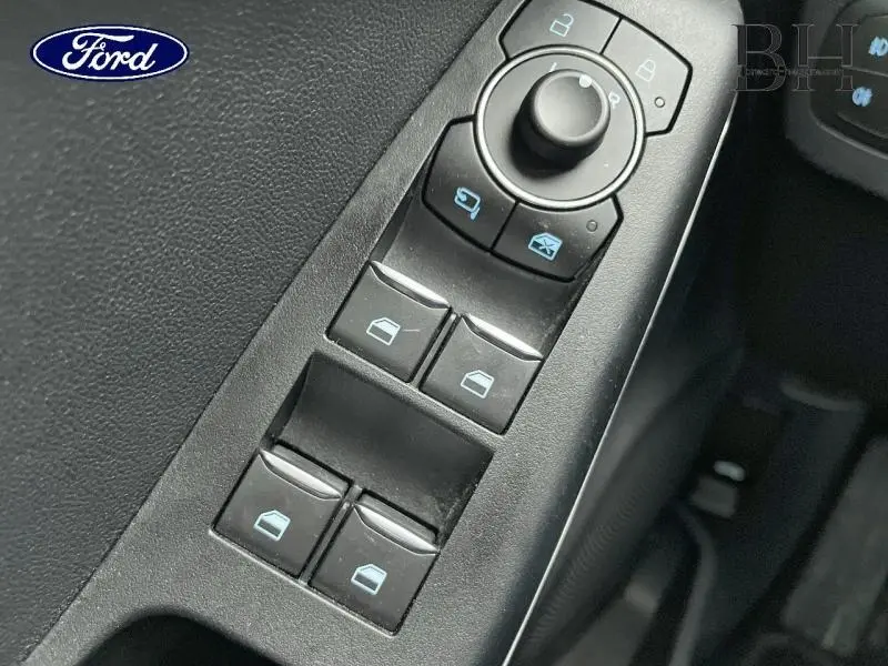 Gros plan sur les commandes des vitres électriques et rétroviseurs dans l'habitacle du Ford Puma gris Solar Métallisée 2022.