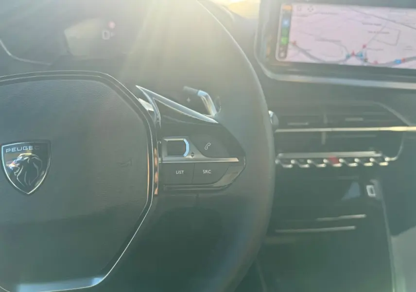 Vue intérieure rapprochée du volant noir du Peugeot 2008 Hybrid 136 Allure avec écran tactile et commandes au volant.