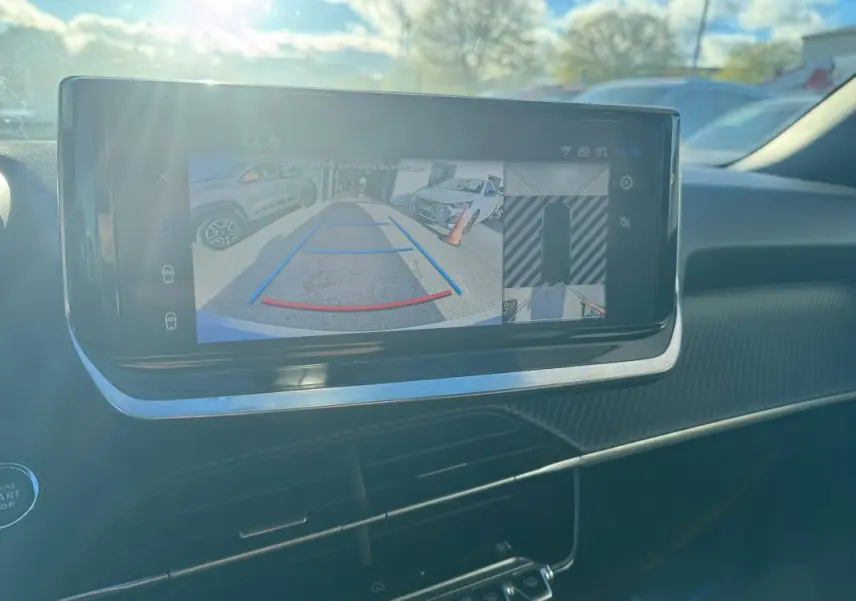 Écran tactile intérieur du Peugeot 2008 Hybrid 136 en vue rapprochée montrant la caméra de recul et l'aide au stationnement.