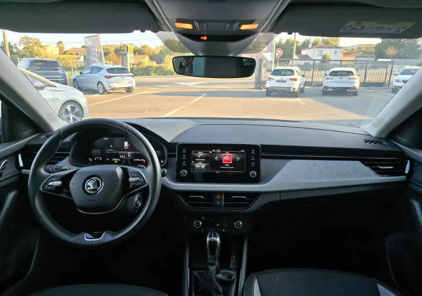 Vue intérieure avant du tableau de bord de la Skoda Scala 2024 gris graphite avec écran tactile et volant multifonctions.