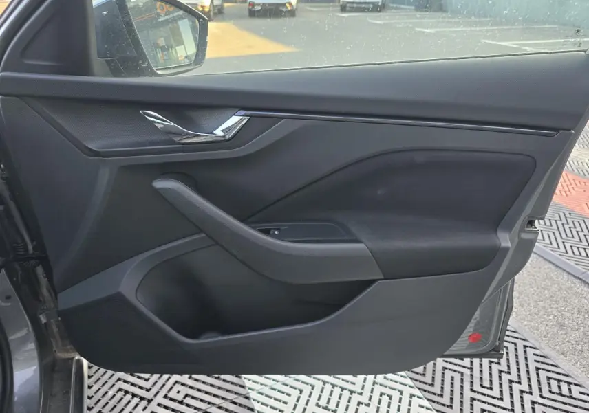 Vue intérieure de la porte avant gauche d'une Skoda Scala 2024 gris graphite, avec poignée chromée et commandes vitres.