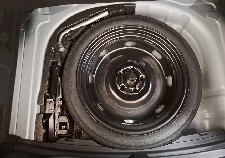 Vue en plongée sur la roue de secours et le cric dans le coffre d'une CUPRA Leon 2024, gris magnétique mat.