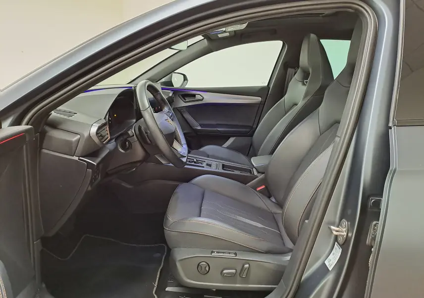 Vue intérieure côté conducteur de la CUPRA Leon 2024 gris magnétique mat avec sièges sport et toit ouvrant panoramique.