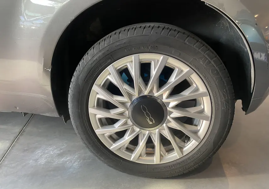 Gros plan sur la roue avant droite d'une FIAT 500 gris foncé avec jante alliage à rayons fins.