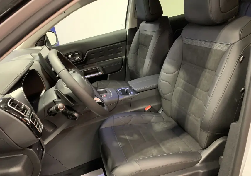 Commandes de réglage électrique des sièges en gros plan dans l'habitacle sombre d'une Citroën C5 Aircross hybride blanche 2024