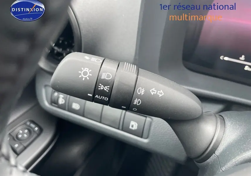 Gros plan sur la commande des phares et clignotants à gauche du volant dans l'habitacle du Toyota C-HR améthyste 2024.