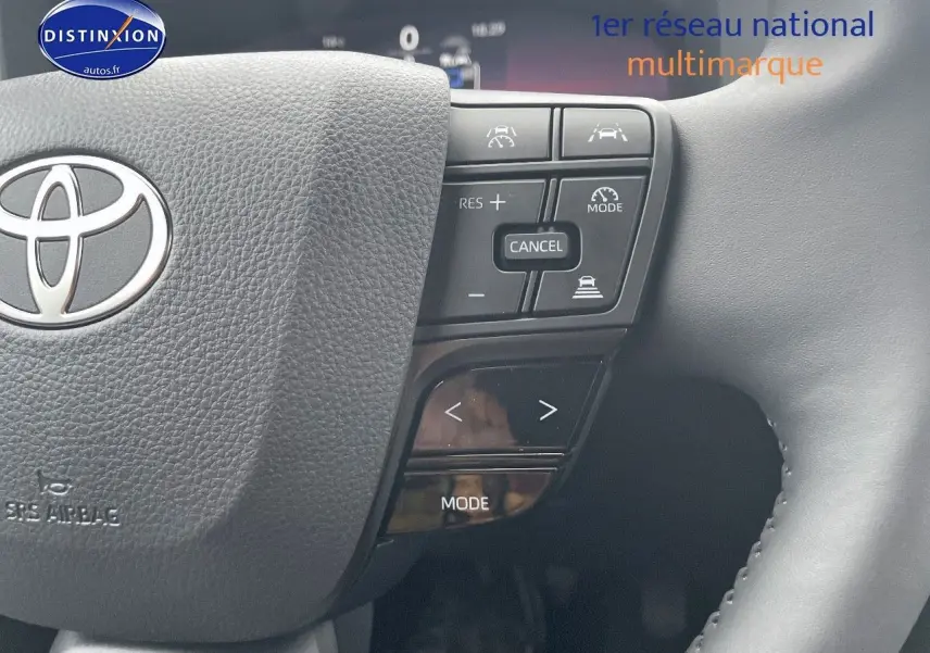 Gros plan sur le volant noir du Toyota C-HR 1.8 Hybrid 2024 avec commandes intégrées et logo Toyota visible.