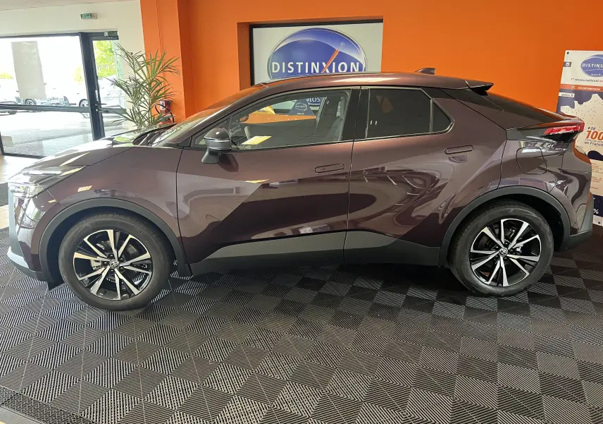 Profil côté gauche du Toyota C-HR 1.8 Hybrid 2024 en améthyste métal, avec jantes alliage bicolores et lignes sculptées.