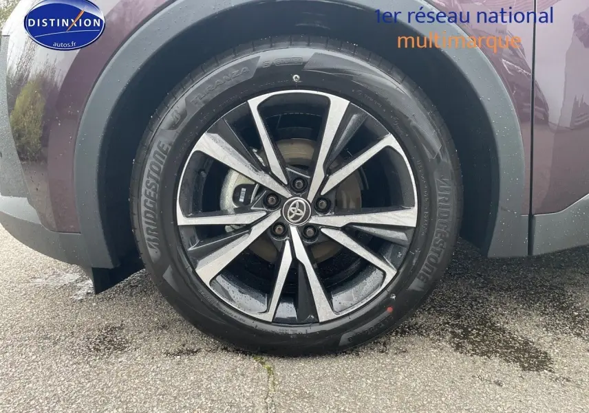 Gros plan sur la roue avant gauche du Toyota C-HR 1.8 Hybrid 2024 en couleur Améthyste métal avec jante alliage bicolore.