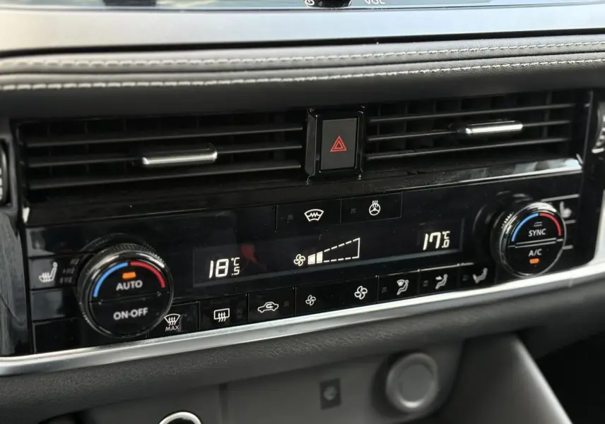 Tableau de bord du Nissan Qashqai 2025 montrant la climatisation automatique bi-zone avec commandes digitales et boutons noirs.