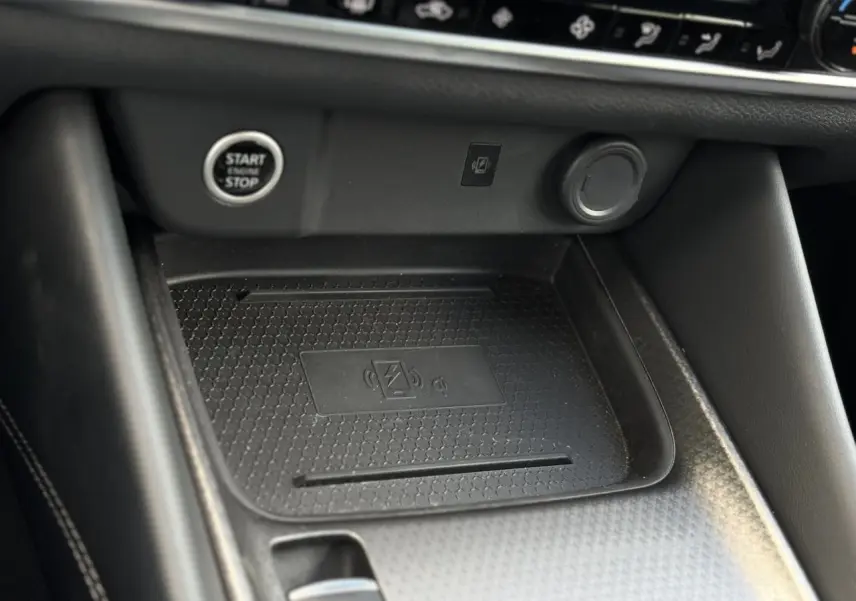 Gros plan sur la zone de recharge sans fil et bouton Start/Stop dans l'habitacle noir du Nissan Qashqai 2025.