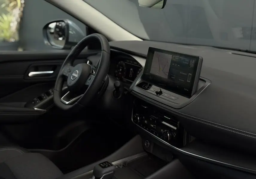 Intérieur du Nissan Qashqai 2025 vu côté conducteur, tableau de bord noir avec écran tactile et volant cuir.