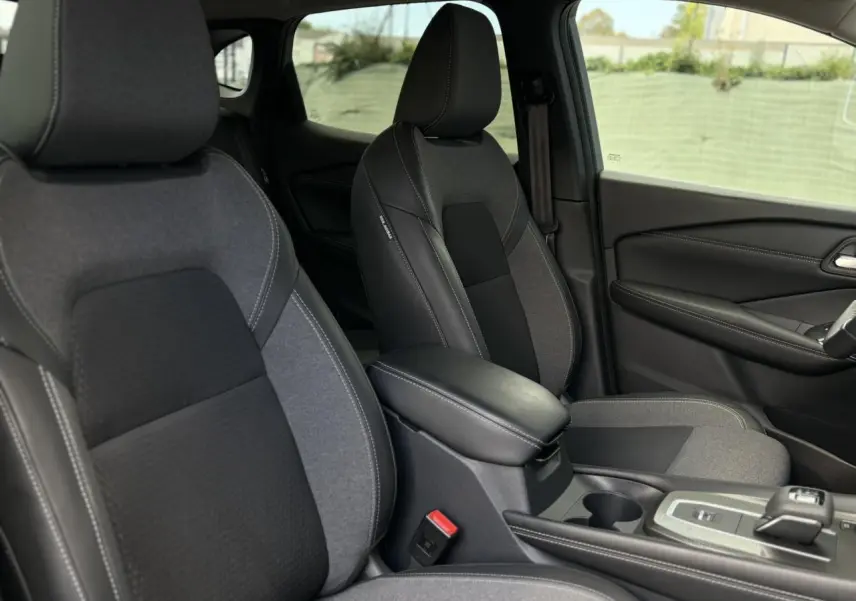Vue intérieure sur les sièges avant gris et noir du Nissan Qashqai 2025 avec accoudoir central et console moderne.