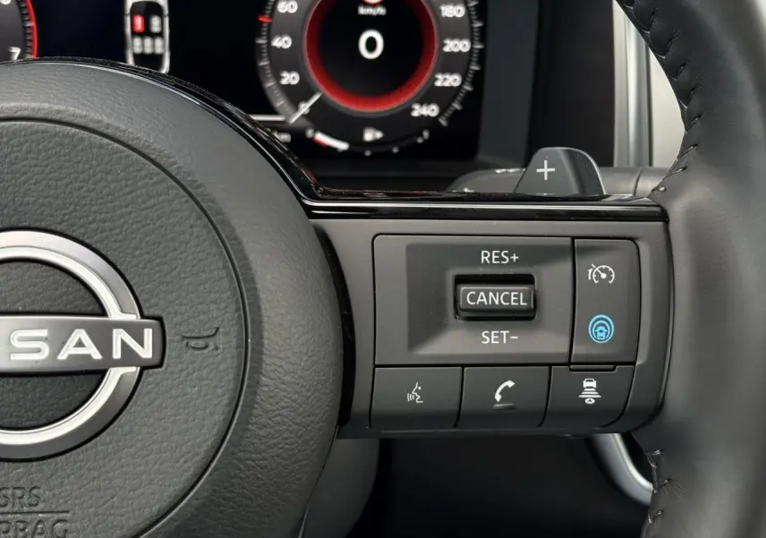 Gros plan sur le volant cuir noir du Nissan Qashqai 2025, avec commandes de régulateur et affichage numérique en arrière-plan.