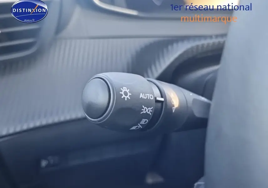 Gros plan sur la commande des phares automatique dans l’habitacle gris d’une Peugeot 208 1.2 100 Allure 2025.