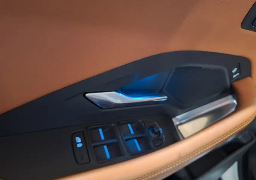 Gros plan sur la garniture cuir marron et les commandes de porte côté conducteur du Jaguar E-PACE blanc 2019.