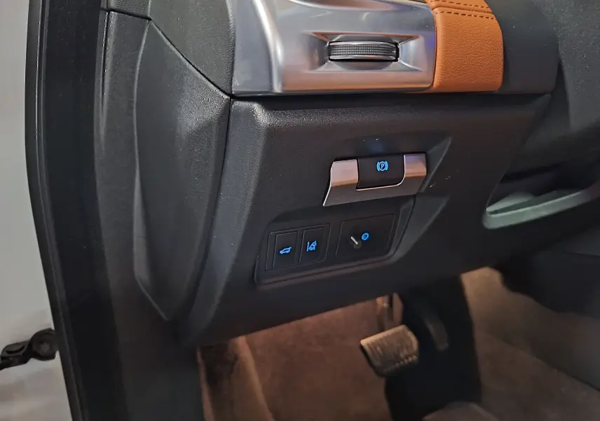 Détail du tableau de bord côté gauche du Jaguar E-PACE blanc 2019 avec commandes électroniques et pédale visible.