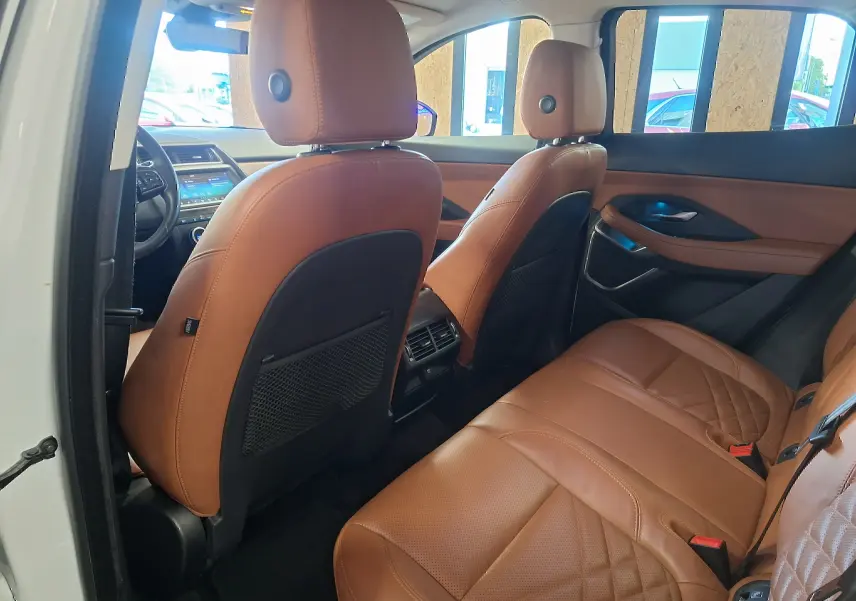 Vue intérieure arrière droite du Jaguar E-PACE blanc 2019 avec sièges en cuir marron et détails de finition raffinée.