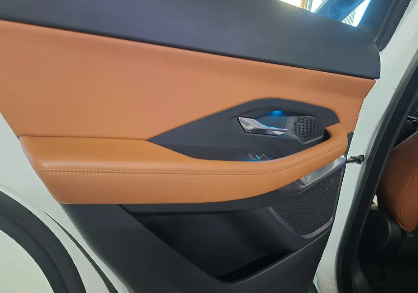 Gros plan sur la porte arrière droite blanche du Jaguar E-PACE 2019 avec garniture cuir marron et poignée argentée.