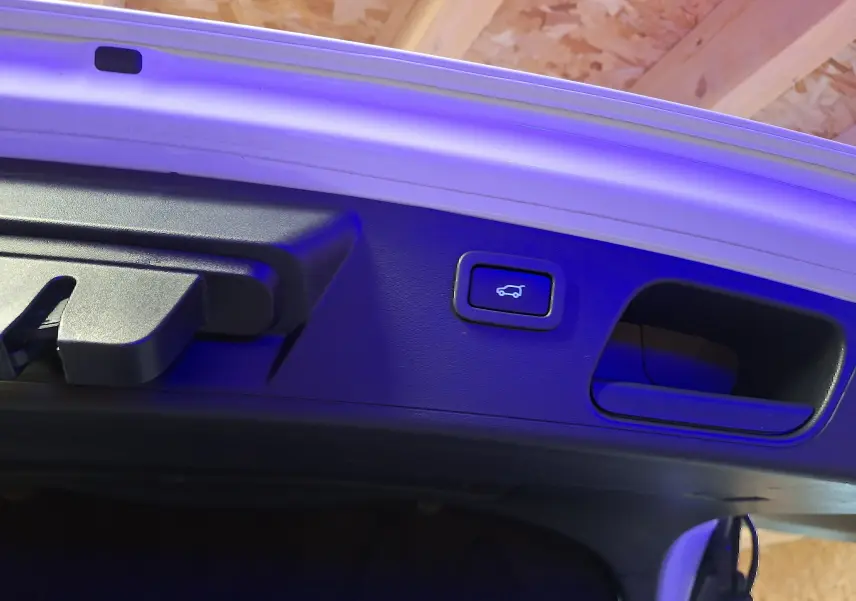Bouton d'ouverture électrique du coffre sur la trappe blanche du Jaguar E-PACE 2019, éclairage bleu léger.