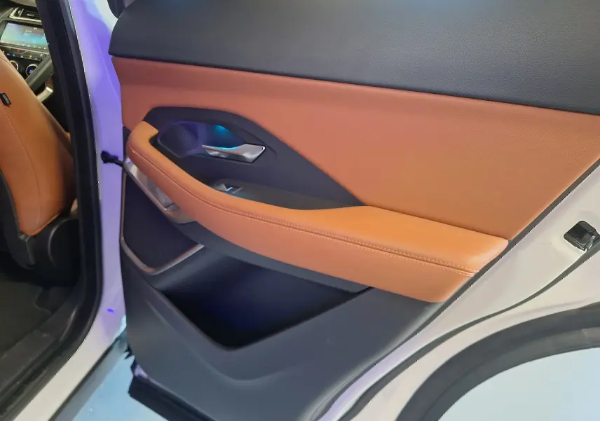 Gros plan sur la garniture cuir marron et noire de la porte arrière gauche du Jaguar E-PACE blanc 2019.