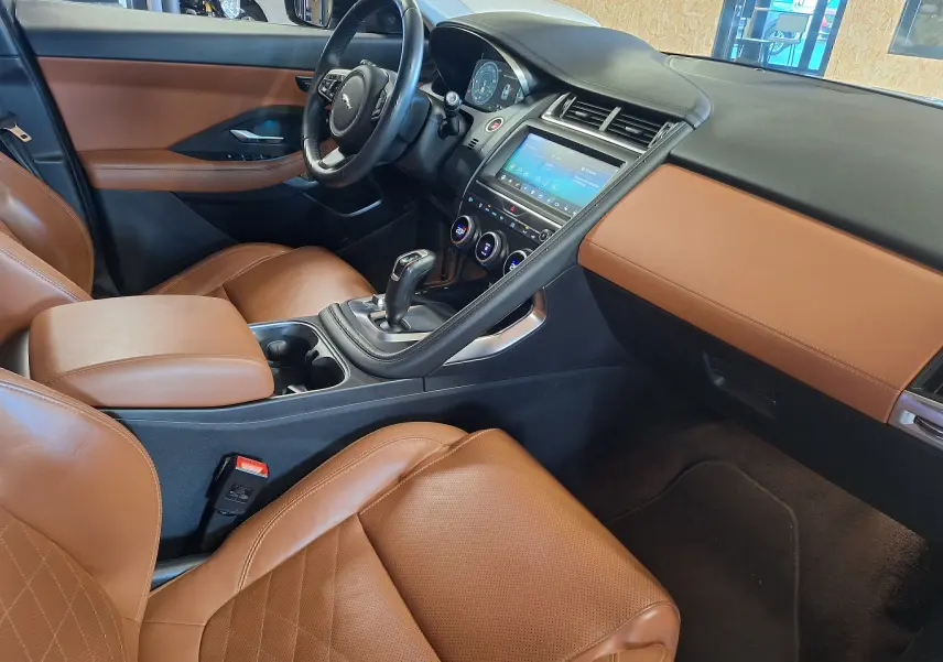 Intérieur côté conducteur du Jaguar E-PACE 2019, sièges cuir marron et tableau de bord avec écran tactile.