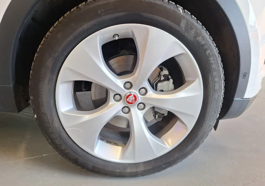Gros plan sur la roue avant droite blanche d'un Jaguar E-PACE 2019 avec jante argentée et logo Jaguar rouge.