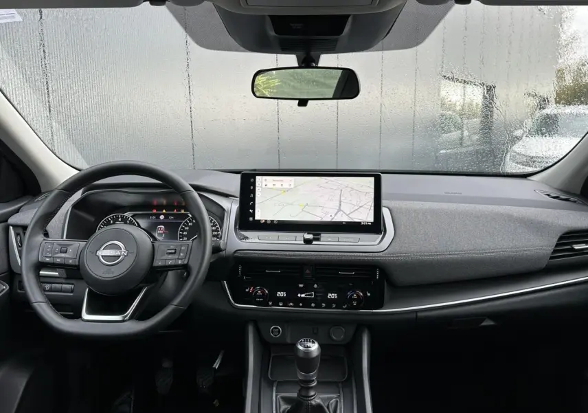 Vue intérieure frontale du tableau de bord noir du Nissan Qashqai 2024 avec écran tactile et boîte manuelle.