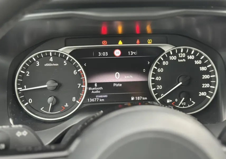 Vue rapprochée du tableau de bord du Nissan Qashqai 2024, affichant compte-tours, vitesse et alertes lumineuses.