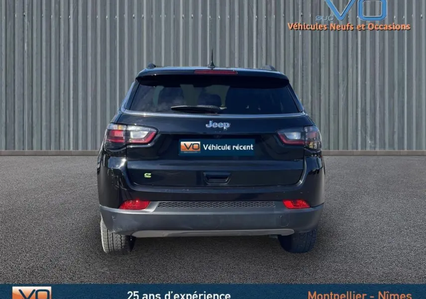 Vue arrière d'un Jeep Compass noir 2023 avec barres de toit et feux arrière LED visibles sur fond neutre.