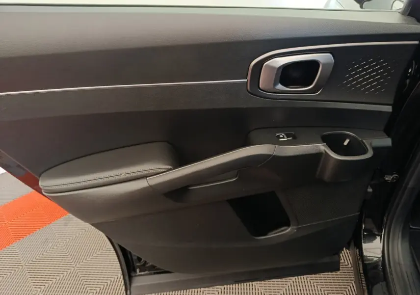 Vue intérieure côté gauche de la porte arrière noire du Kia Sorento 2023 avec poignée argentée et accoudoir rembourré.
