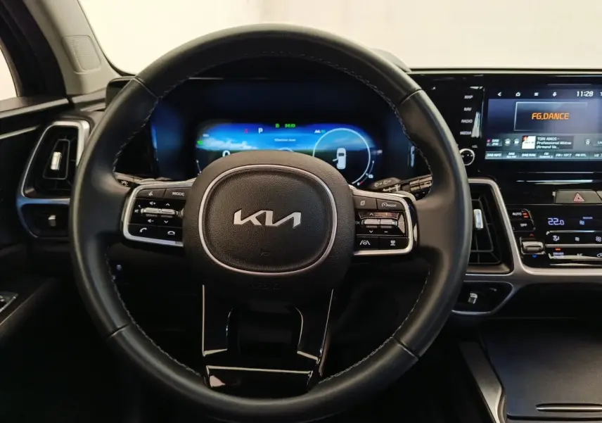 Vue intérieure centrée sur le volant noir du Kia Sorento 2023 avec tableau de bord digital et écran tactile.