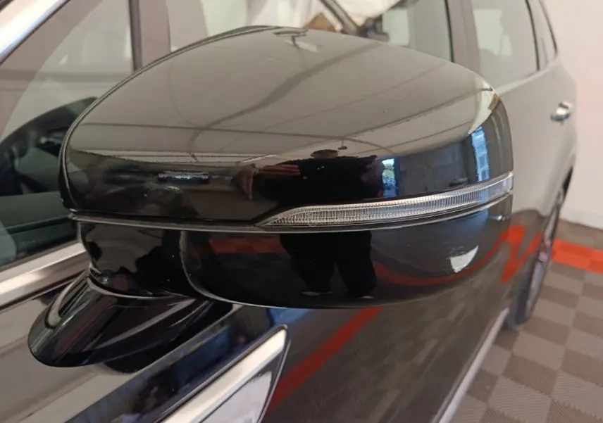 Gros plan sur le rétroviseur droit noir brillant du Kia Sorento 2023 hybride rechargeable, avec clignotant intégré.