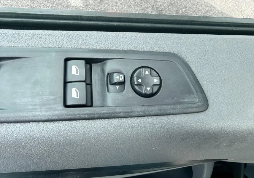 Détail des commandes de réglage des vitres et des rétroviseurs sur la porte côté conducteur d'un Citroën Jumpy blanc.