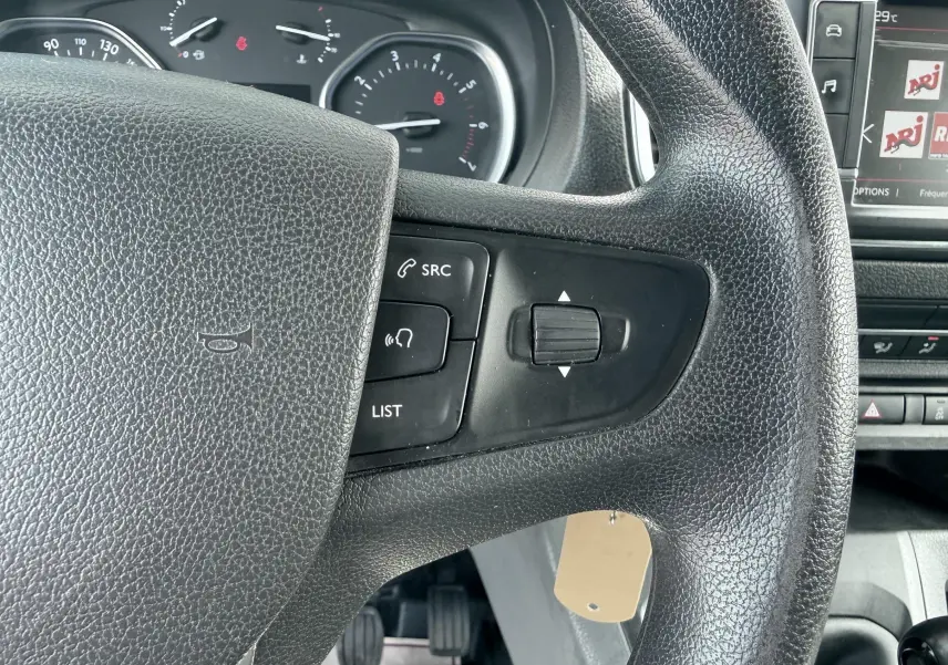 Gros plan sur le volant noir du Citroën Jumpy avec commandes intégrées, tableau de bord et écran multimédia partiellement visibles.