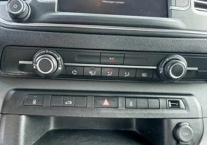 Vue rapprochée du tableau de bord noir du Citroën Jumpy blanc, montrant les commandes de climatisation et boutons fonctionnels.