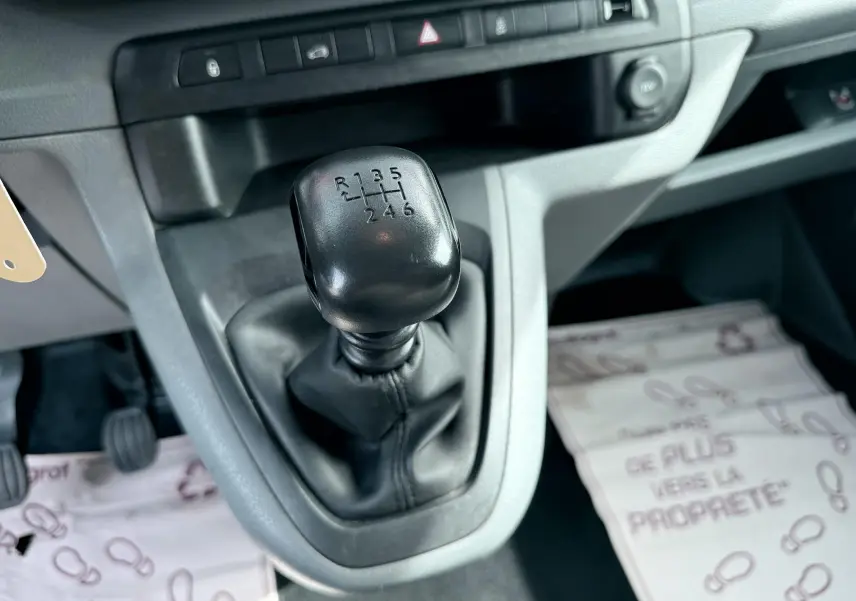 Gros plan sur le levier de vitesses manuel noir dans l’habitacle gris clair du Citroën Jumpy blanc de 2017.