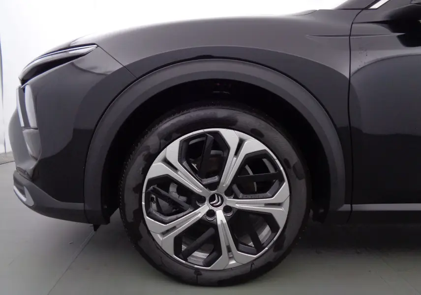 Gros plan sur la roue avant droite noire métallisée du Citroën C5 X 2023 avec jante alu bicolore distinctive.