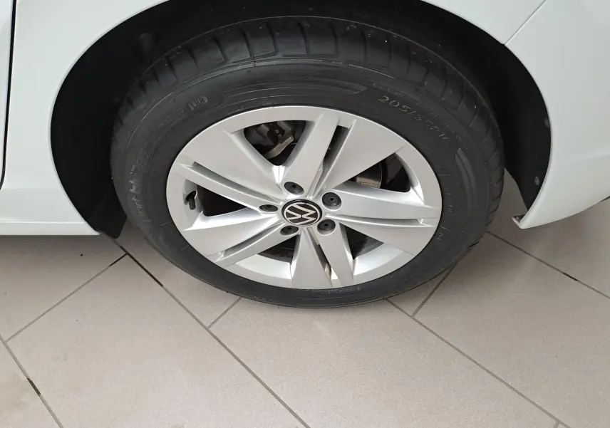 Gros plan sur la roue avant gauche de la Volkswagen Golf blanche avec jante en alliage à 5 branches.