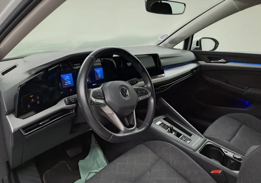 Intérieur moderne de Volkswagen Golf 1.5 TSI 2022, vue côté conducteur avec tableau de bord numérique et éclairage bleu.