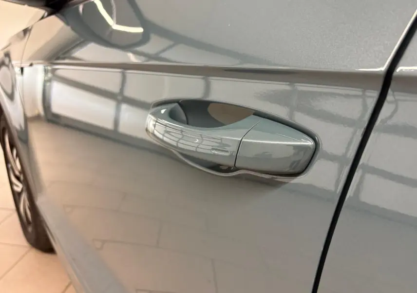 Poignée de porte côté gauche d'un Volkswagen T-Roc bleu pétrole 2024 avec peinture métallisée brillante.