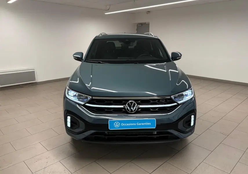 Volkswagen T-Roc 2024 bleu pétrole vu de face, avec projecteurs IQ.Light Matrix LED allumés et finition R-Line.