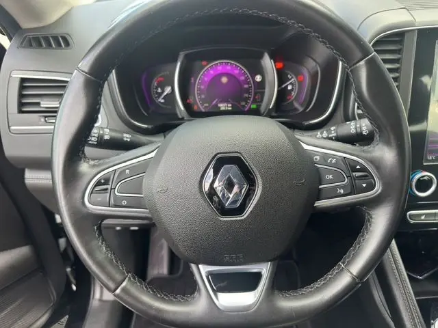 Volant en cuir noir de Renault Koleos 2017 avec commandes intégrées, cadrans lumineux et tableau de bord moderne visible en arrière-plan.
