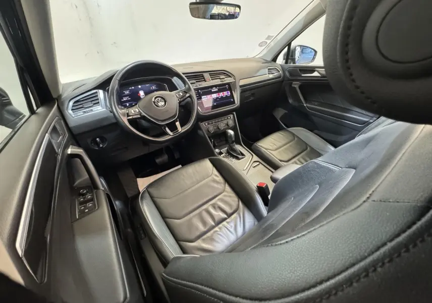 Vue intérieure côté conducteur du Volkswagen Tiguan Allspace 2019, sièges cuir noirs et tableau de bord digital.